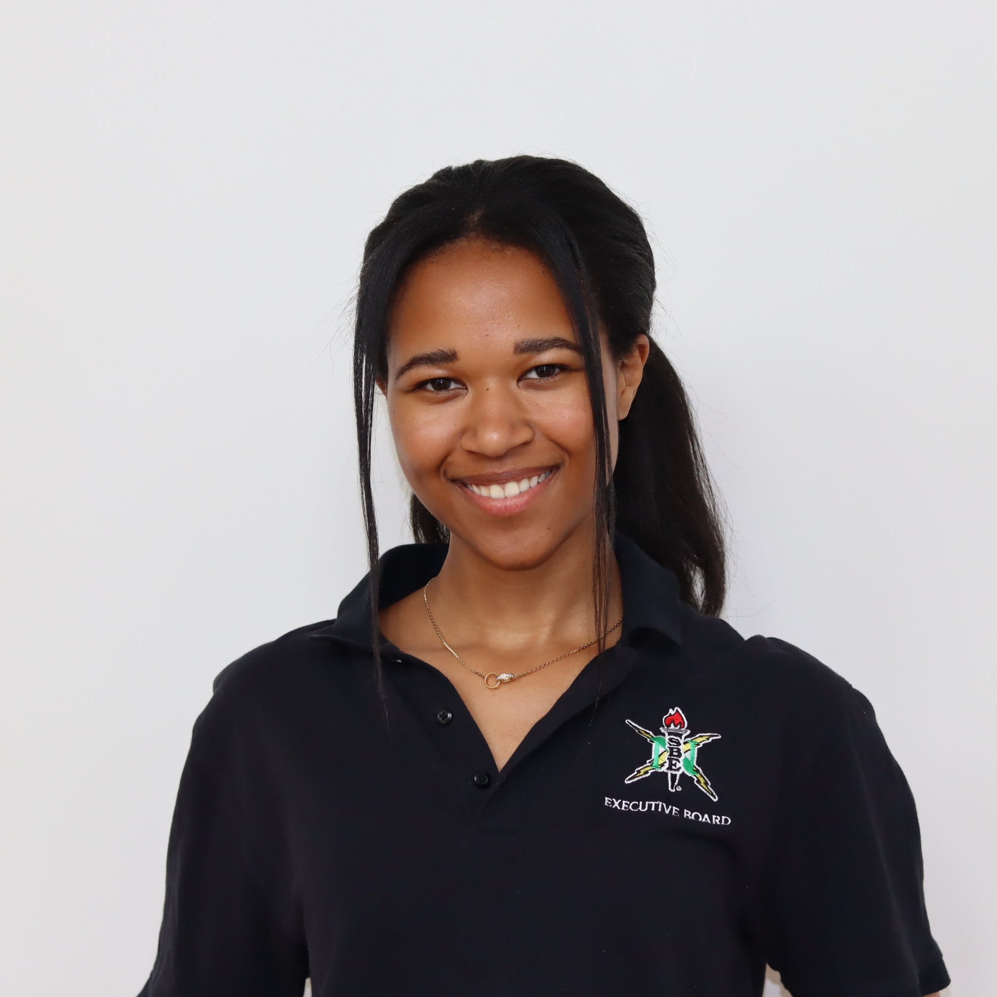 Person wearing a black polo shirt with a logo on a white background