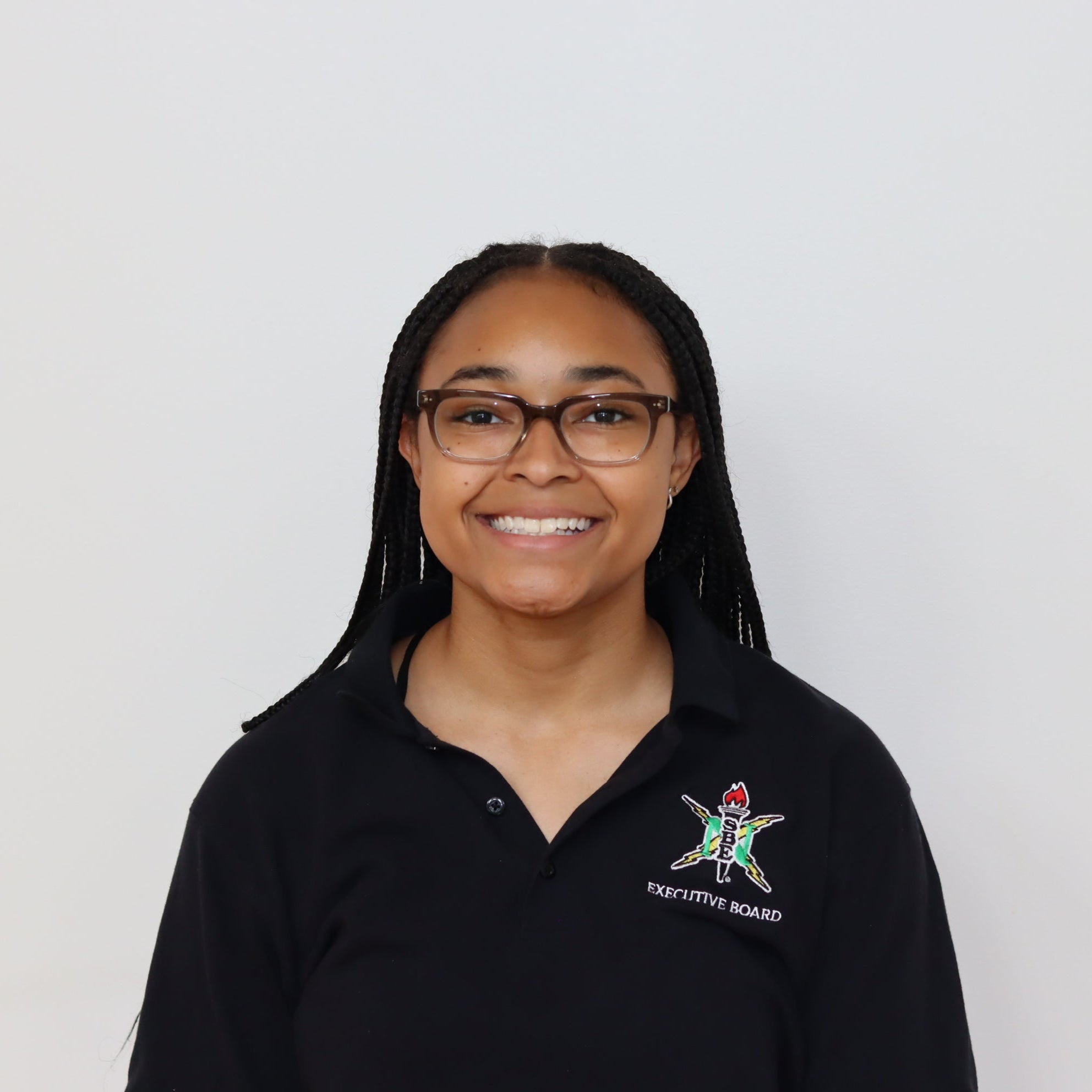 Person wearing a black polo shirt with a logo on a white background