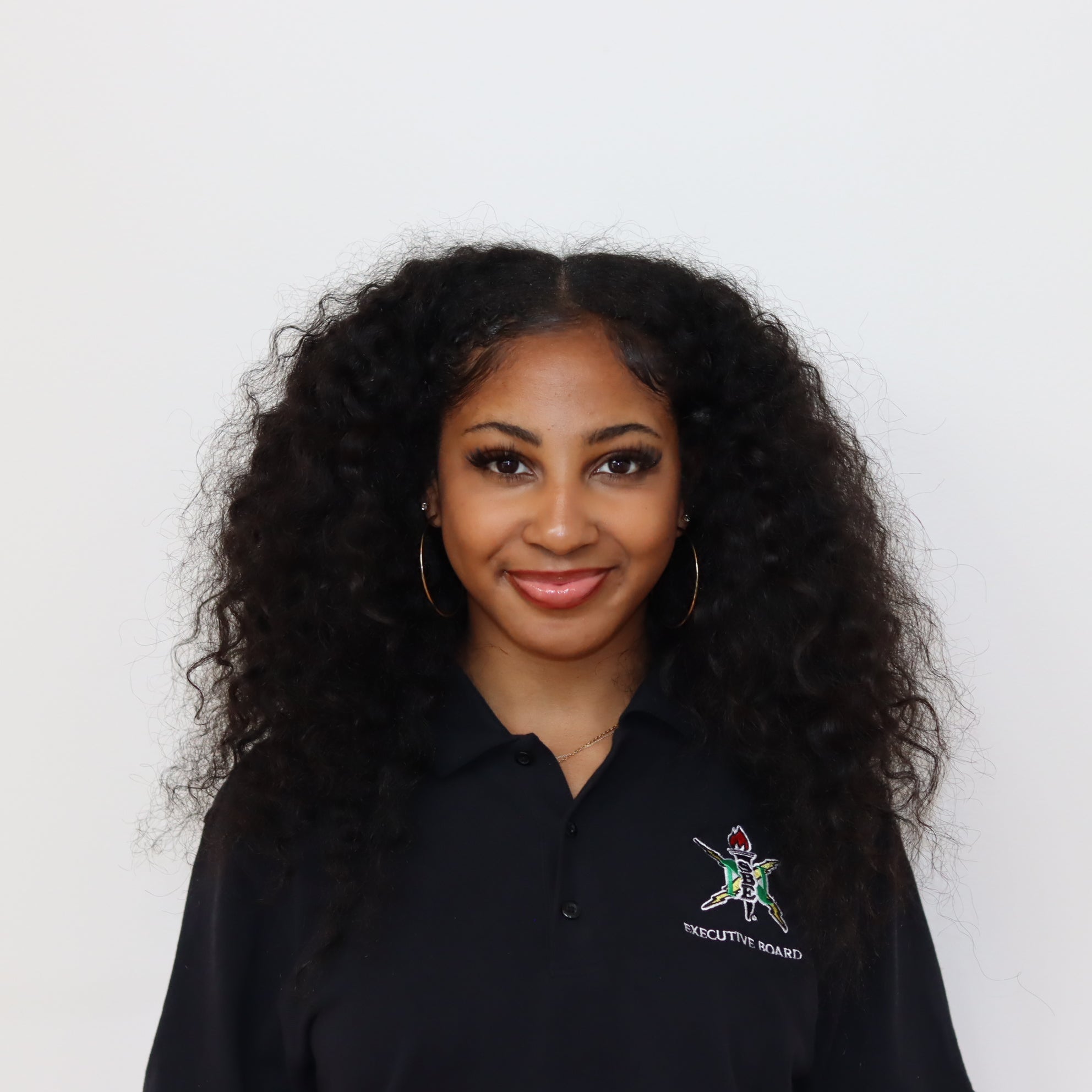 Woman wearing a black polo shirt with a logo on a white background