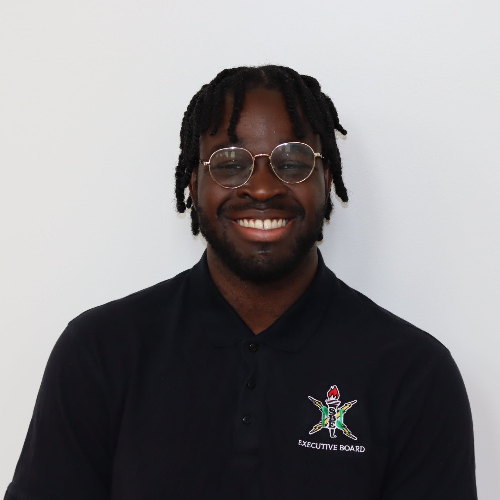 Man wearing a black polo shirt with a logo on a white background