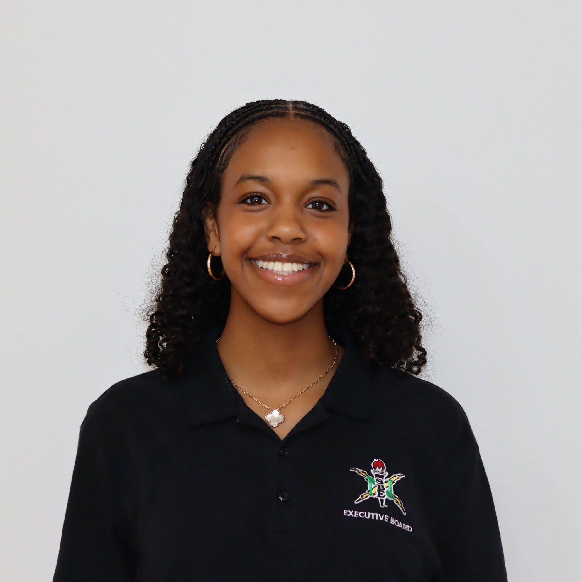 Person wearing a black polo shirt with a logo on a light gray background