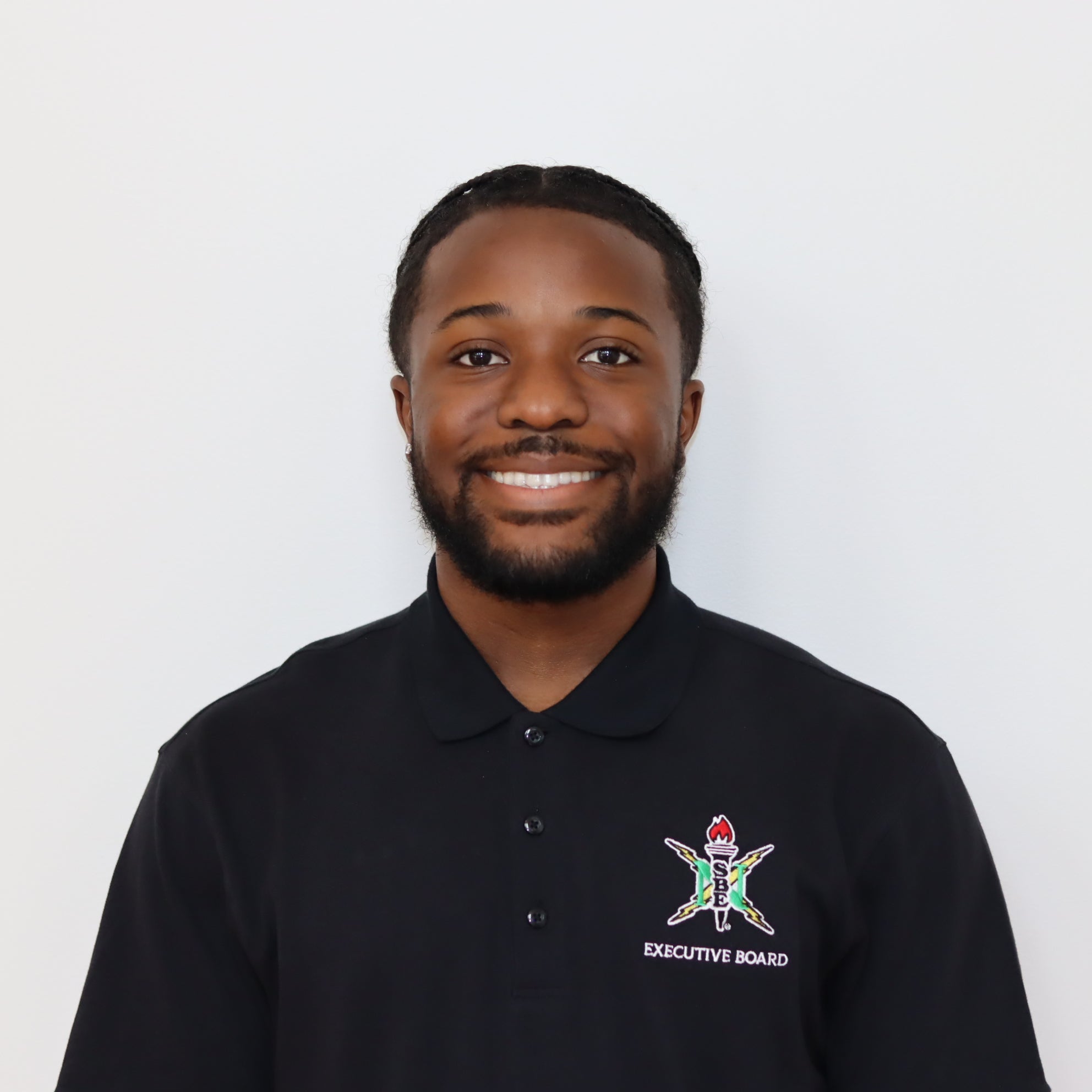 Man wearing a black polo shirt with a logo on a white background